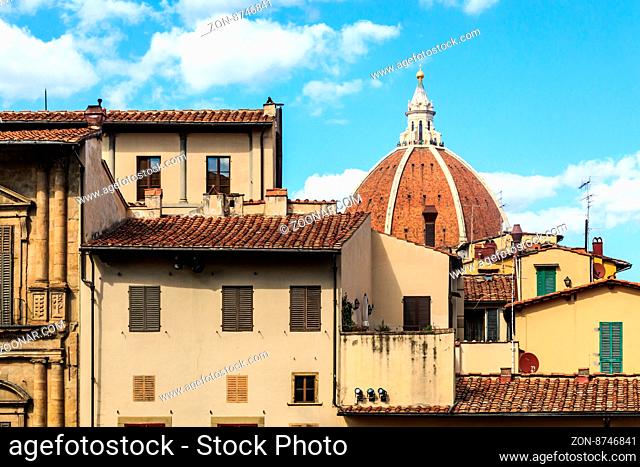 Close up top view of Florence houses with orange roofs and with a big dome, on cloudy blue sky background