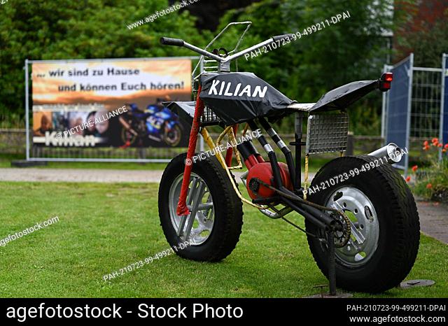 23 July 2021, Lower Saxony, Leer: A motorcycle sculpture stands in front of a house, on whose fence hangs a banner with the inscription "".