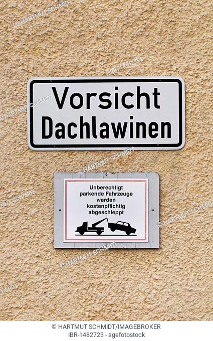 Two signs, Vorsicht Dachlawinen, caution roof avalanches, and Unberechtigt parkende Fahrzeuge werden kostenpflichtig abgeschleppt