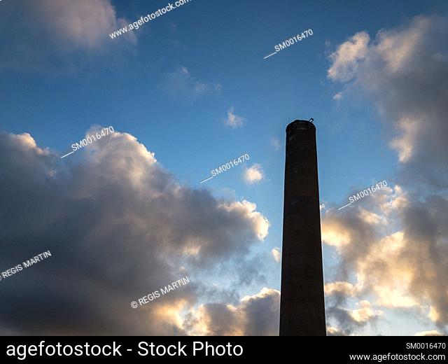 Tall chimney smokestack against cloudy sky