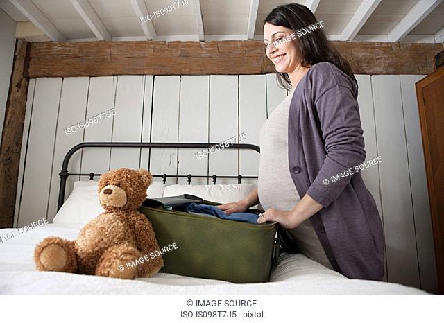 Expectant mother packing suitcase