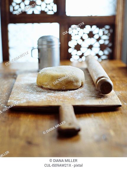 Dough, rolling pin on wooden chopping board, making bread