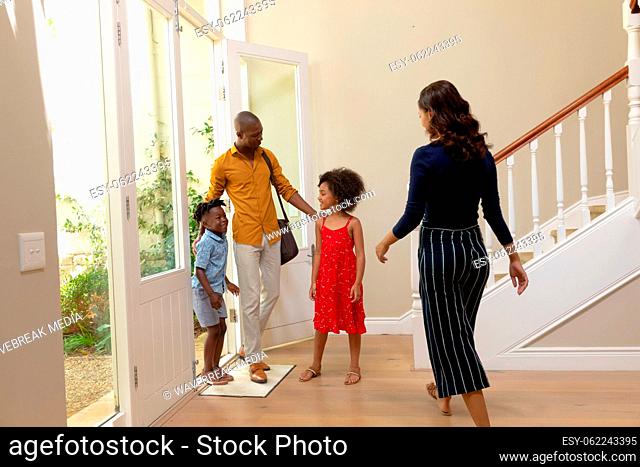 Mixed race couple and their young son and daughter standing in the hallway of their home