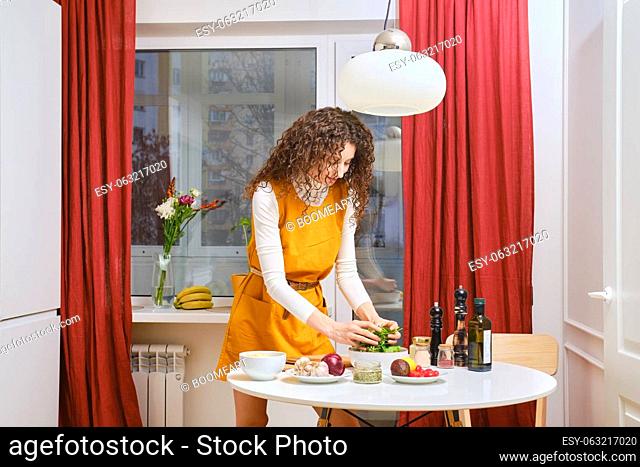 Young woman tossing fresh vegetables for probiotic salad in the bowl