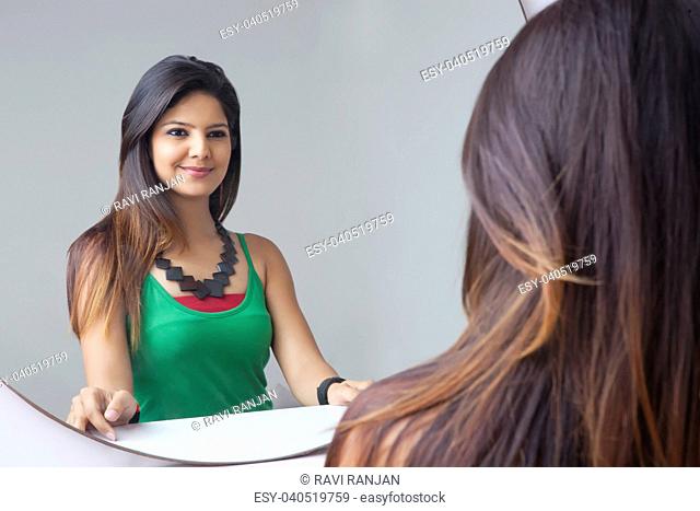 Young woman looking at herself in the mirror