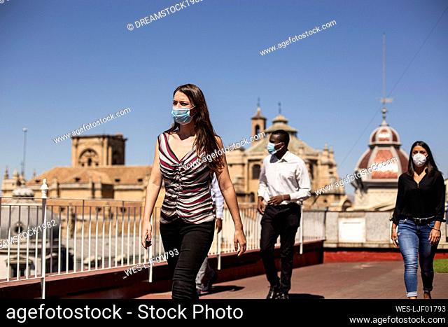 Business people wearing masks while walking at rooftop of office building