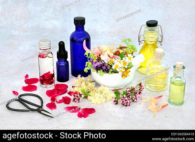 Summer herb & flower selection for preparing aromatherapy essential oils with oil bottles and flowers in a mortar with pestle and loose