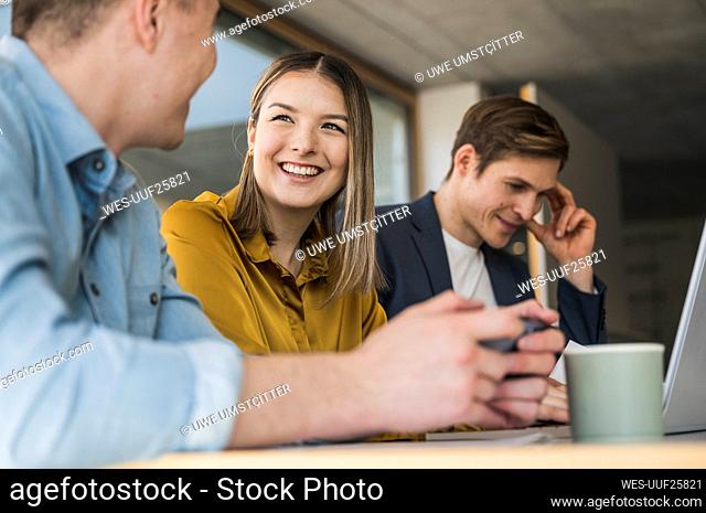 Smiling business people with smartphone and laptop in office