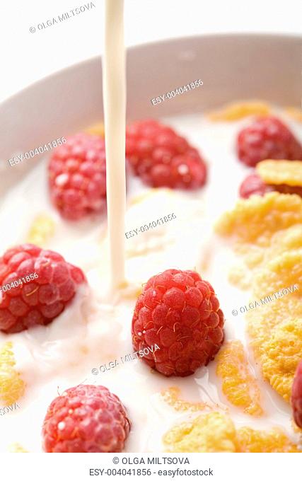 milk pouring onto muesli with raspberry isolated