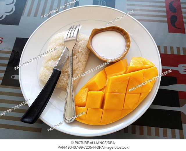 14 March 2019, Thailand, Karon Beach: Sticky Riche with mango, glutinous rice with mango and coconut sauce, a typical Thai specialty, on a plate