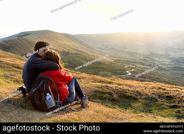 Young couple embracing while looking at sunset during vacations
