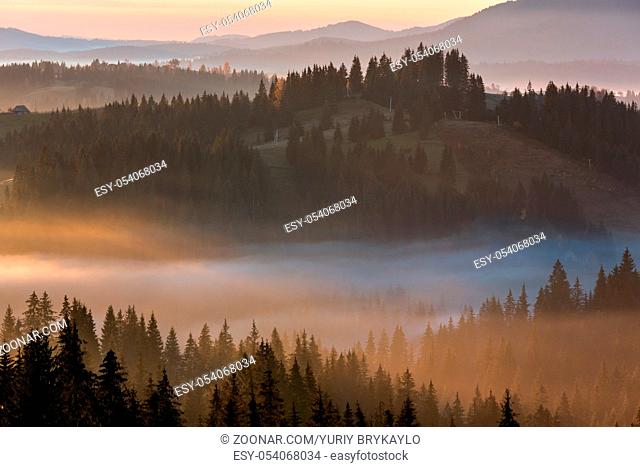 The air. Early morning fog and first morning sun rays over the autumn slopes of Carpathian Mountains (Yablunytsia village and pass, Ivano-Frankivsk oblast