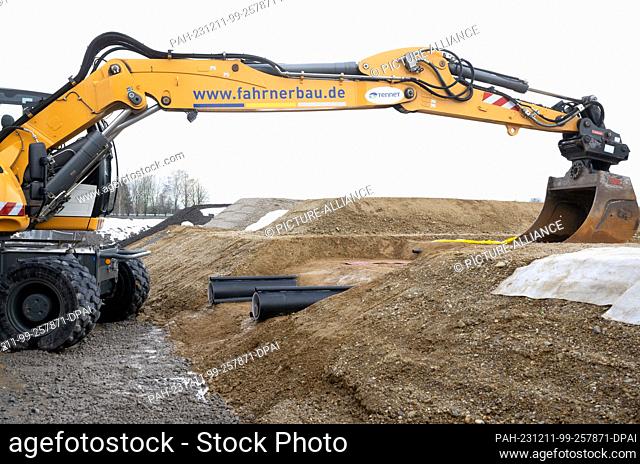 11 December 2023, Bavaria, Niederaichbach: An excavator and two cables can be seen during the symbolic opening of the construction site for the south-east link