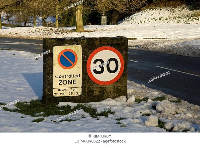 England, North Yorkshire, Hutton le Hole, Snow carpets the ground beside a 30 mph speed limit sign in Hutton le Hole