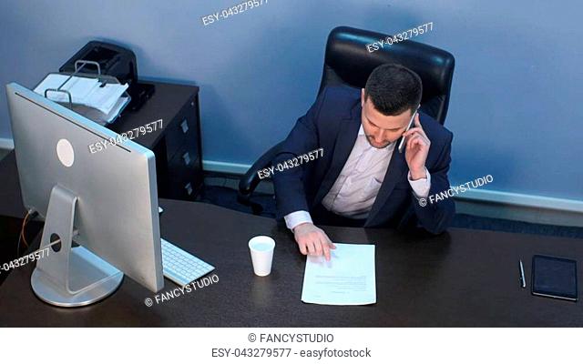 Businessman talking on phone and working on computer in office. Top view. Professional shot in 4K resolution. 085. You can use it e.g