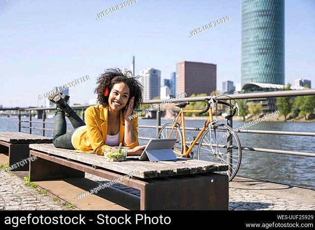 Smiling businesswoman listening music and using laptop on sunny day