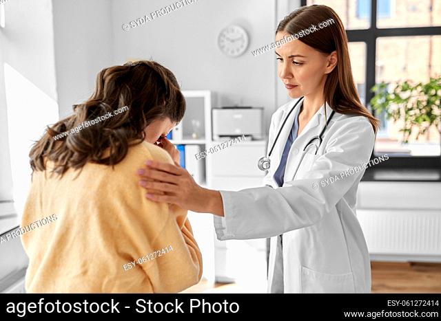 female doctor comforting sad woman at hospital