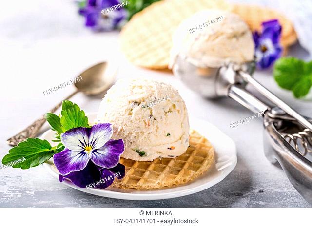 Vanilla ice cream scoop with edible flowers pansy. Summer food concept