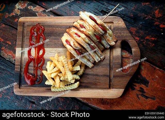 Top view of sandwiches with Turkish sausage (sucuk) and cheese served aise with french fries isolated on rustic wooden table