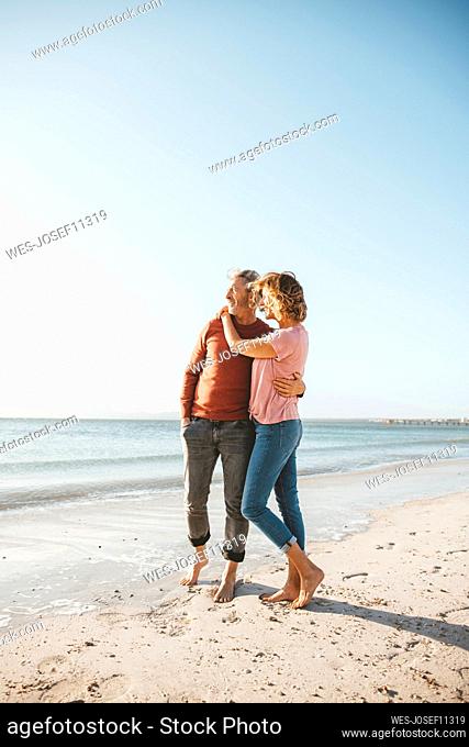Mature couple standing on shore at beach