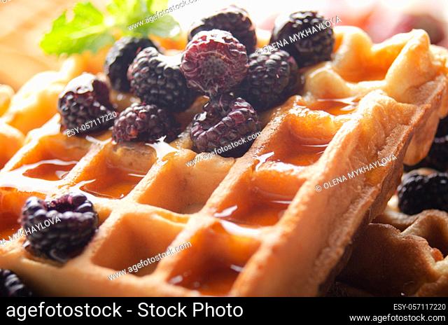 Homemade crispy Belgian waffles served with blackberries and honey closeup