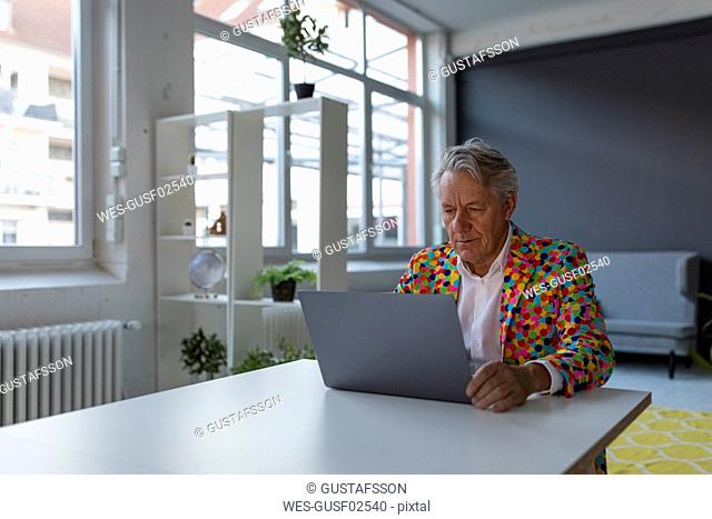 Senior businessman wearing colorful sports jacket using laptop