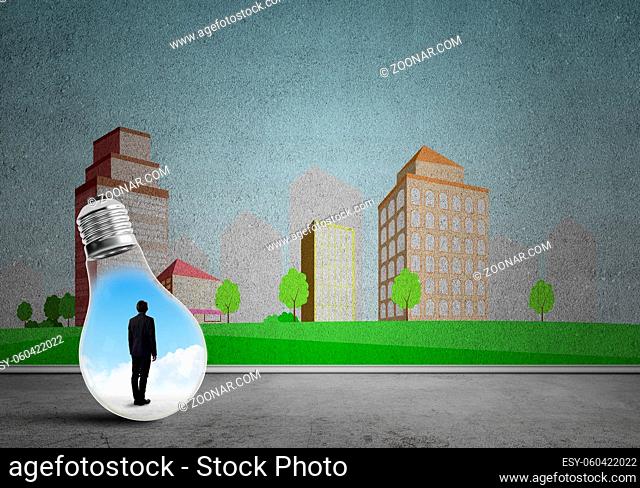 Businessman inside light bulb against city drawn concept