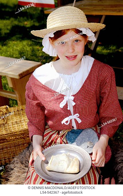 Girl in costume eating pieCirca 1700 reenactment of the Colonial period lifestyle in Southeastern Michigan at the Feaste of Sainte Claire Port Huron Michigan