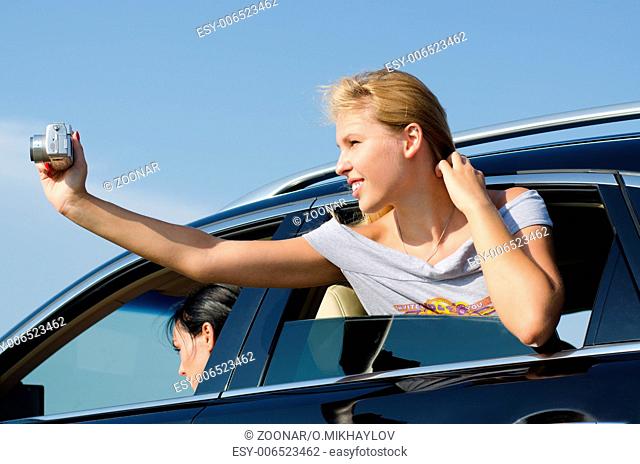 Young woman taking photos from a car