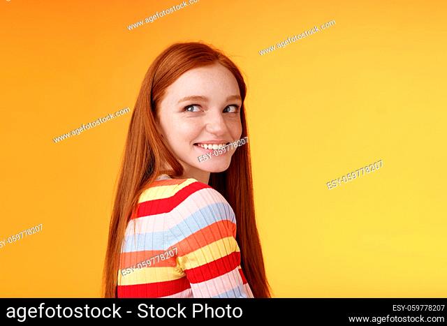 Tender romantic carefree european redhead girlfriend turning behind look left amused smiling pleased coquettish gaze standing orange background flirty romantic...