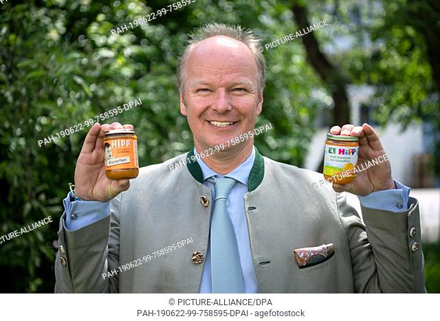 04 June 2019, Bavaria, Pfaffenhofen: Stefan Hipp, Managing Director of Hipp Holding, holds the first glass of baby food from 1960 and the latest Hipp glass in...