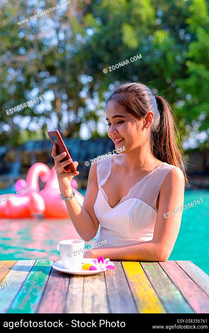 Portrait of young beautiful Asian tourist woman relaxing by the lake outdoors