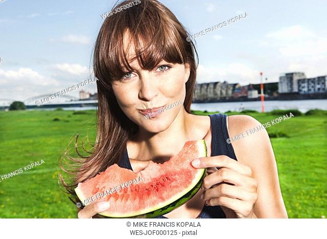 Germany, Cologne, Young woman eating watermelon, portrait
