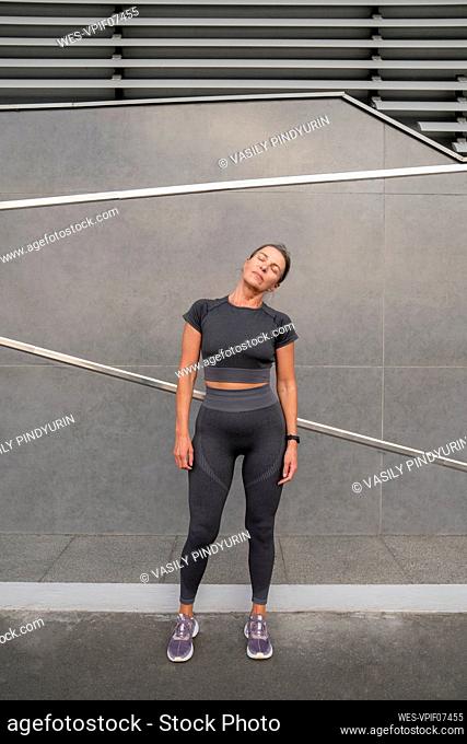 Mature woman doing warm up exercise in front of wall