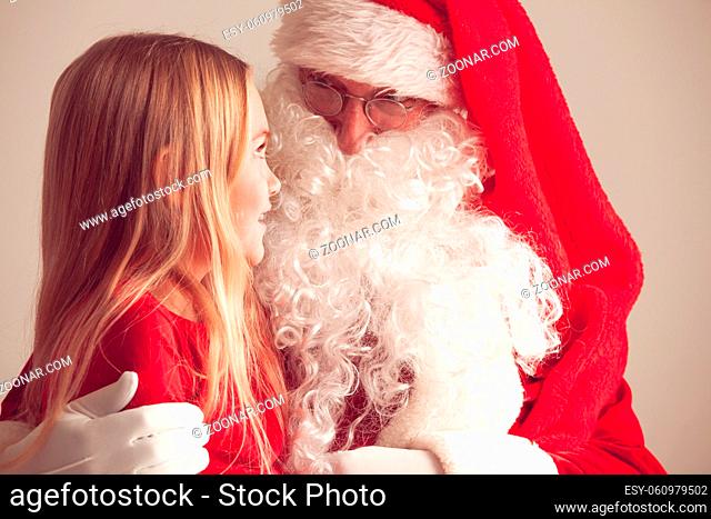 Portrait of smiling little girl sitting on santa claus knees