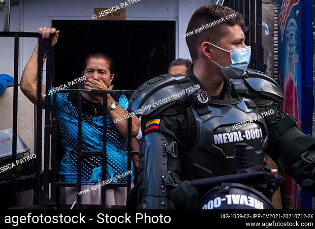 A women inside her house stands behind a riot police officer (ESMAD) amid a dangerous construction area, Colombia's child services (ICBF) and riot police...