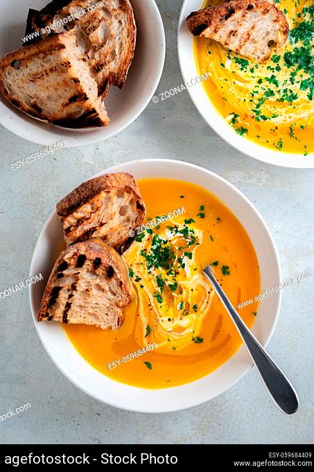 Pumpkin soup served in a bowl with croutons, parsley and olive oil. High quality photo