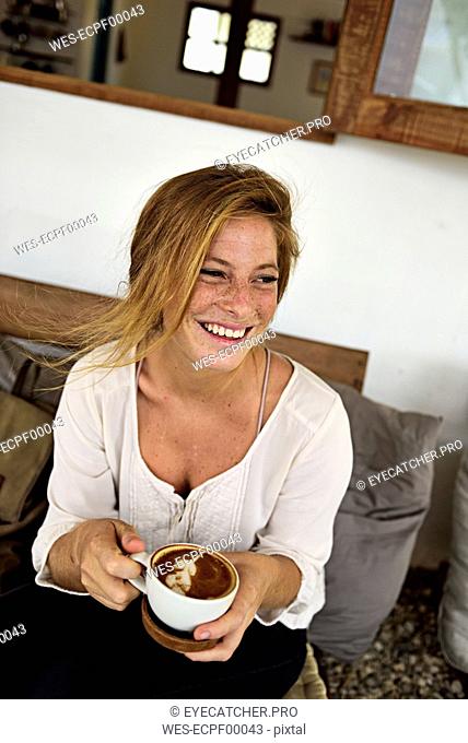 Portrait of laughing strawberry blonde young woman with cup of coffee