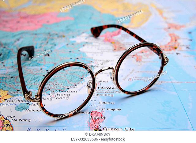 Photo of glasses on a map of Asia. Focus on Hong Kong. May be used as illustration for traveling theme
