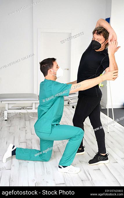Physiotherapist with protective face mask working with a patient during Coronavirus or Covid-19 pandemic. High quality photo