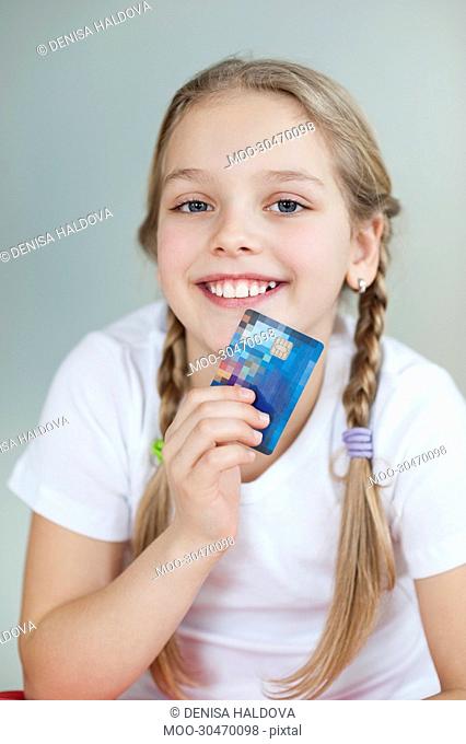 Portrait of a girl holding credit card over gray background