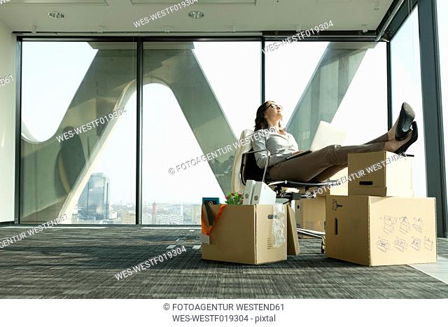 Businesswoman using laptop with feet on cardboard boxes