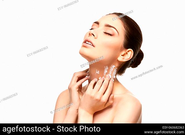 beautiful young woman applying moisturizing skin cream on neck. studio beauty shot on white background. copy space