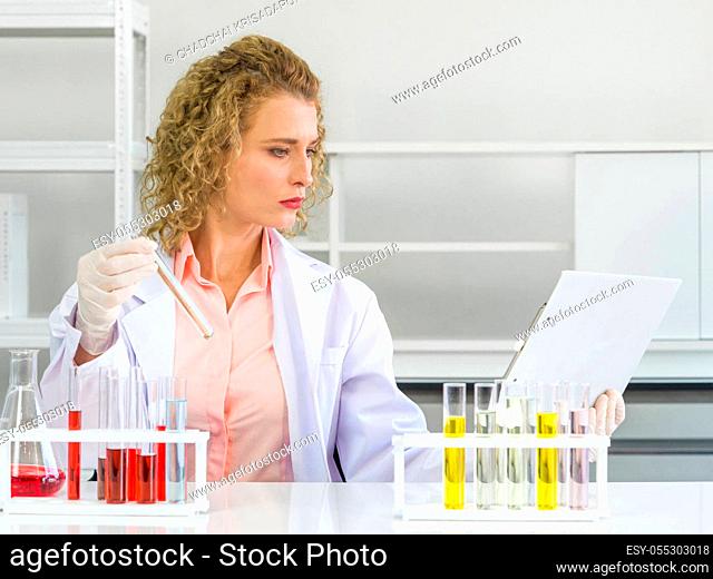 Young blonde scientists are comparing the results of new chemical research with experimental charts on the clipboard. Working atmosphere in chemical laboratory