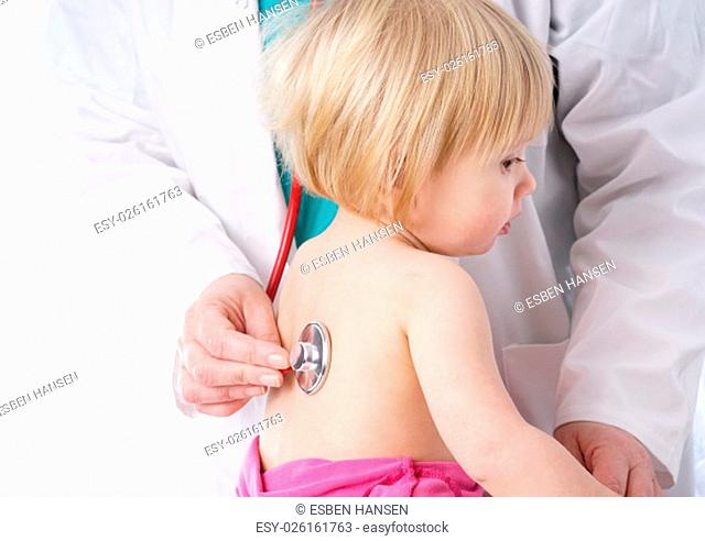 The doctor examines toddler child and listening to heart and lungs with stethoscope. The baby girl is happy, isolated on white
