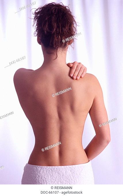 backview - young woman holding her hand on her shoulder