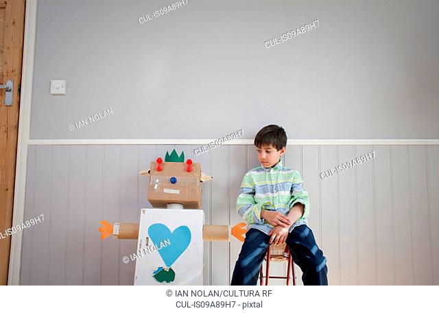 Boy sitting next to homemade toy robot