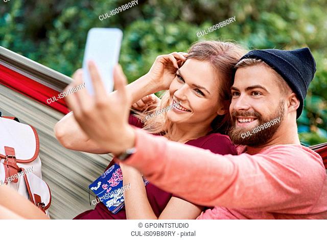 Couple in hammock taking selfie smiling, Krakow, Malopolskie, Poland, Europe