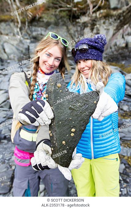 Lynsey Dyer And Sierra Quitiquit Holding Up Heart Shaped Rock On The Beach In Whittier While On A Break During A Backcountry Ski Trip By Snowmobile In Late...