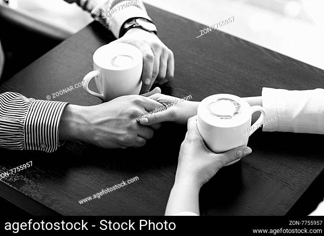 Hands on the table holding cups of coffee